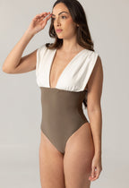 Woman wearing ARIEL luxury swimwear with a deep V-neck and two-tone design in white and brown, posing against a neutral background in a modest, elegant style.