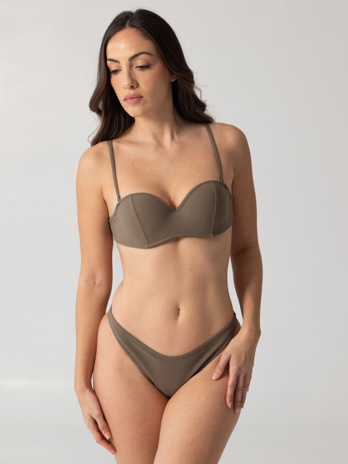 Woman wearing a taupe-colored luxury swimwear bikini named BRUNA, posing against a plain light background in a minimalist style.