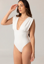 Woman wearing a white ARIEL one-piece swimsuit with a deep V neckline and structured shoulders, showcasing luxury swimwear with a minimalist design.